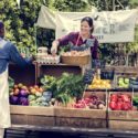 man and woman selling eggs and produce at a farmers market