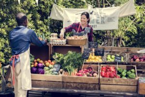 man and woman selling eggs and produce at a farmers market