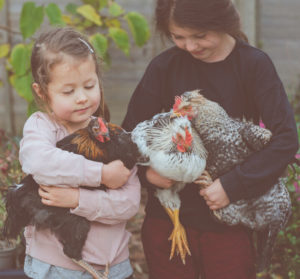 Two girls holding chickens