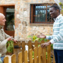 Two neighbors talking across backyard fence