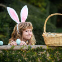 little girl on easter egg hunt wearing bunny ears
