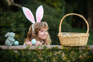 little girl on easter egg hunt wearing bunny ears